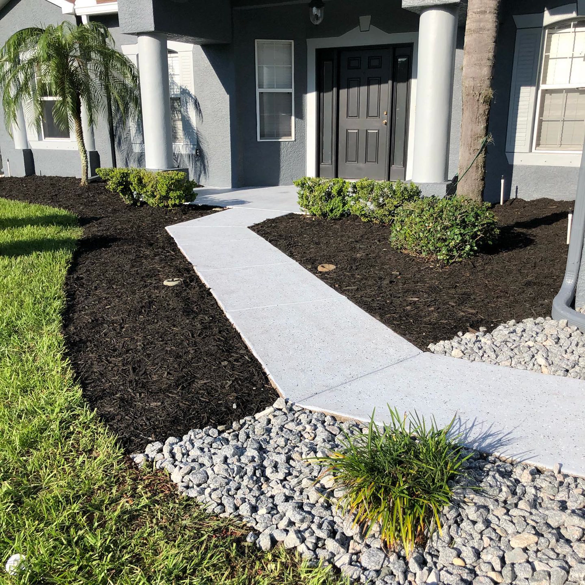 Fresh mulch beds and a white rock path beside a Spring Hill home